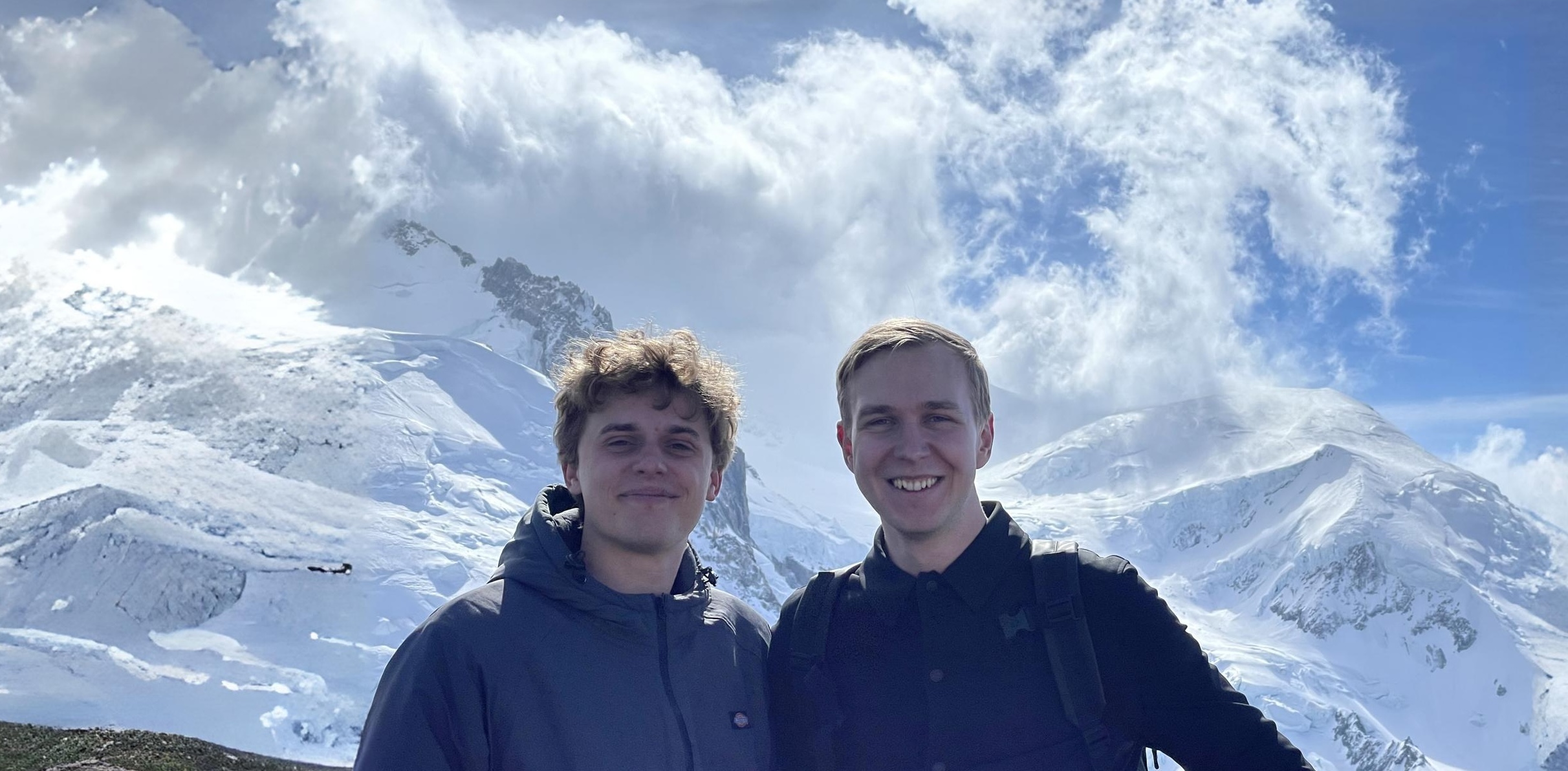 Two nice looking guys standing on top of a mountain